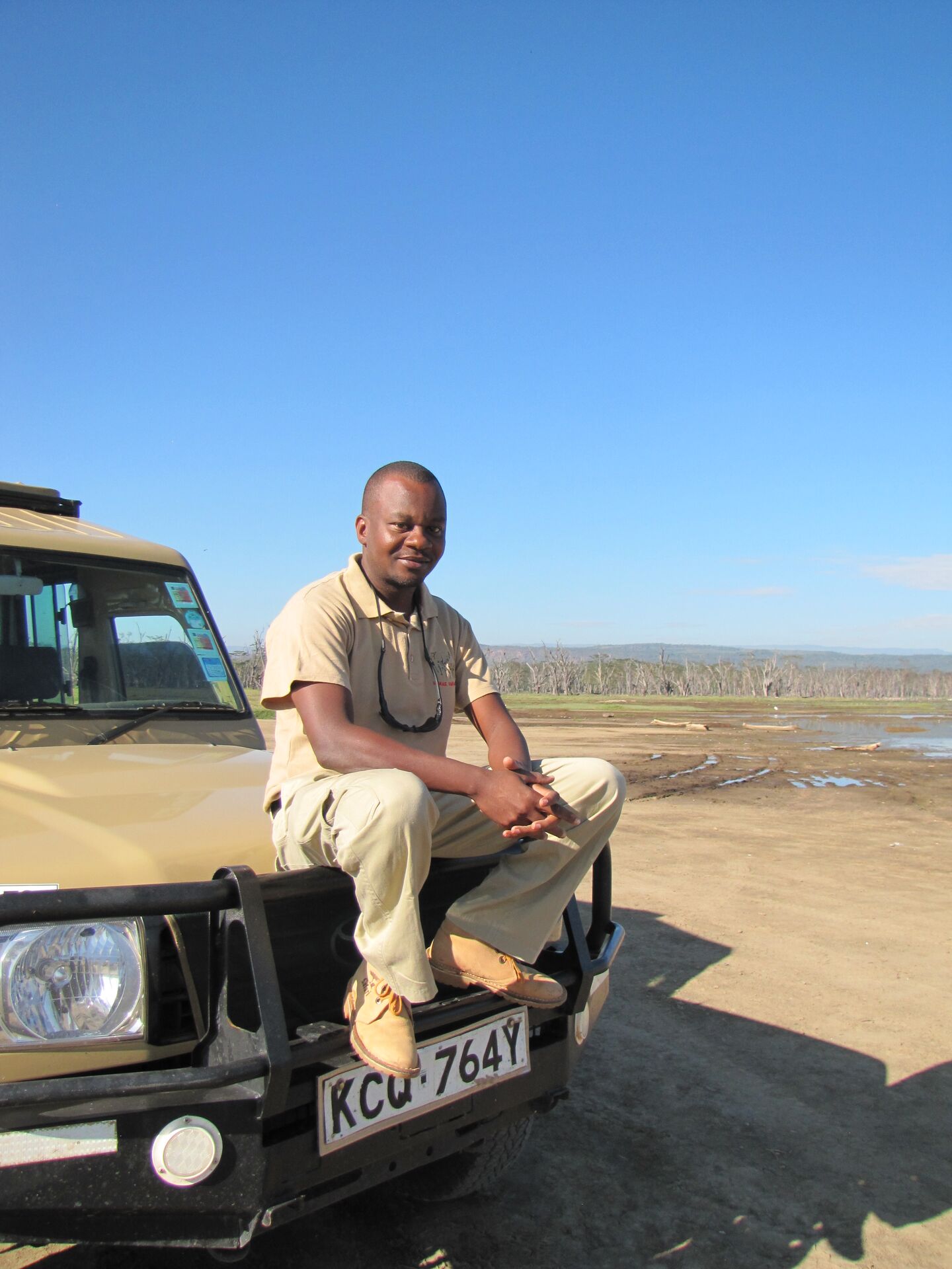 Safari guide Dedan sits on the bonnet of a jeep