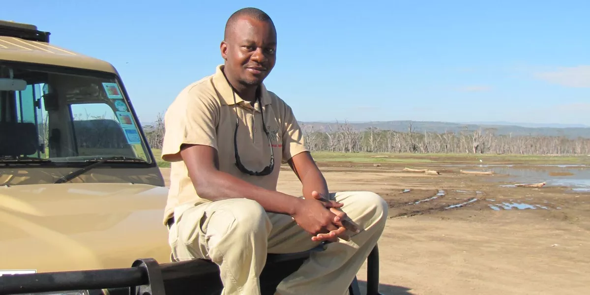 Safari guide Dedan sits on the bonnet of a jeep