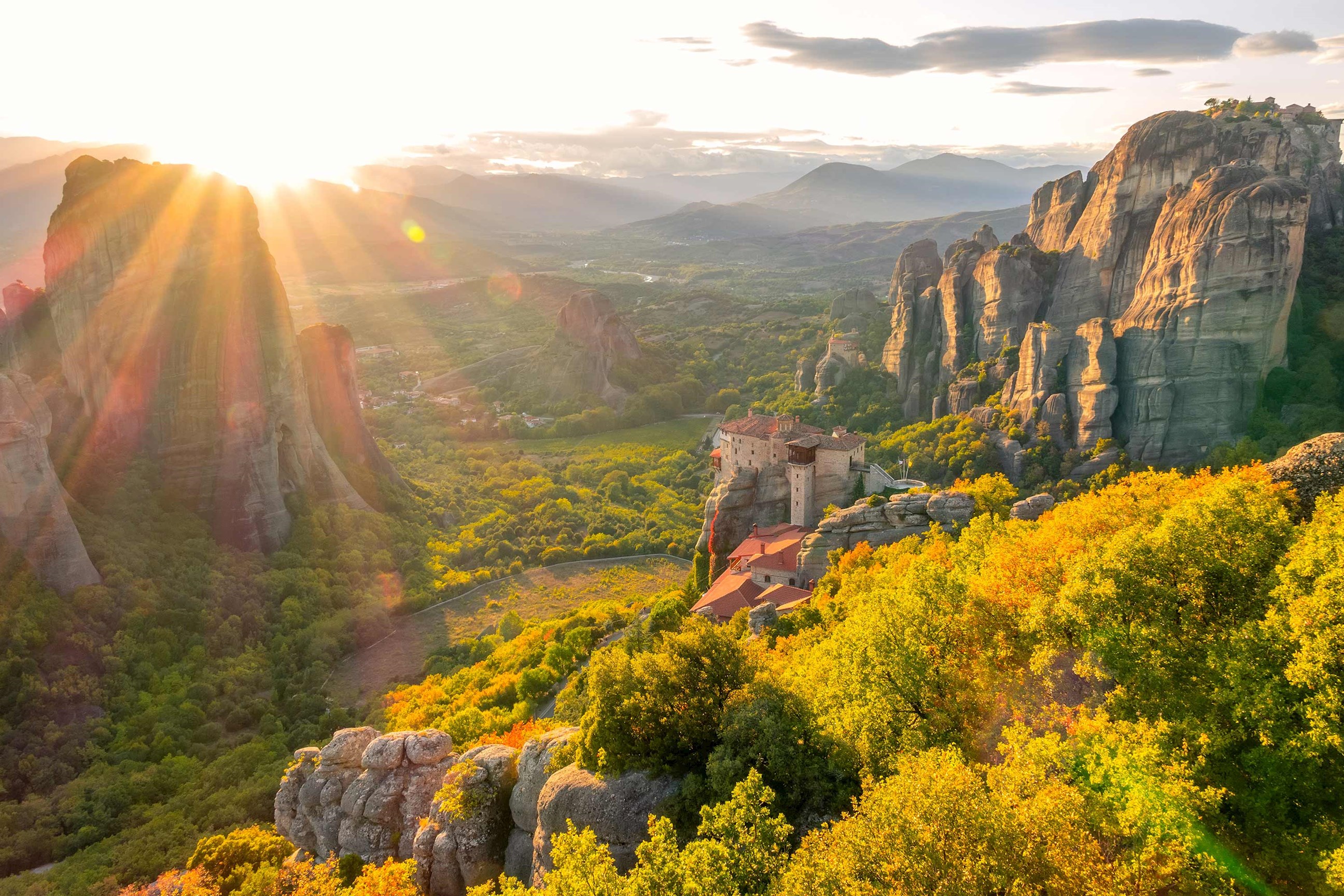 A scenic view of the sun rising over Meteora Monasteries in Greece