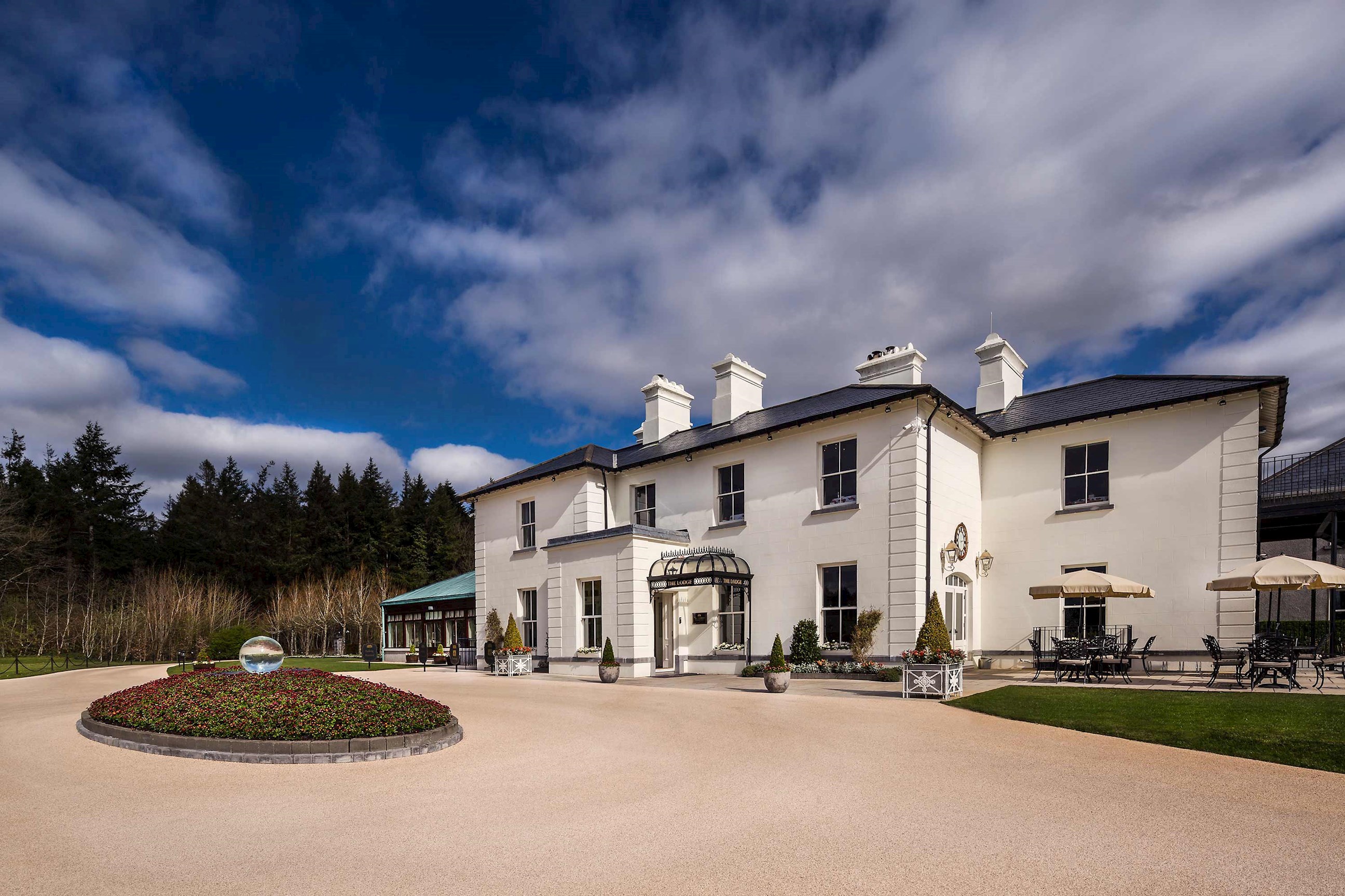 Lodge at Ashford Castle with white facade, gardens and outdoor seating in Cong