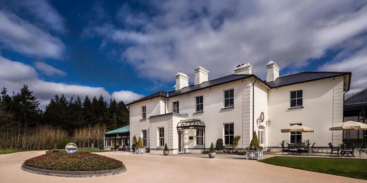 Lodge at Ashford Castle with white facade, gardens and outdoor seating in Cong