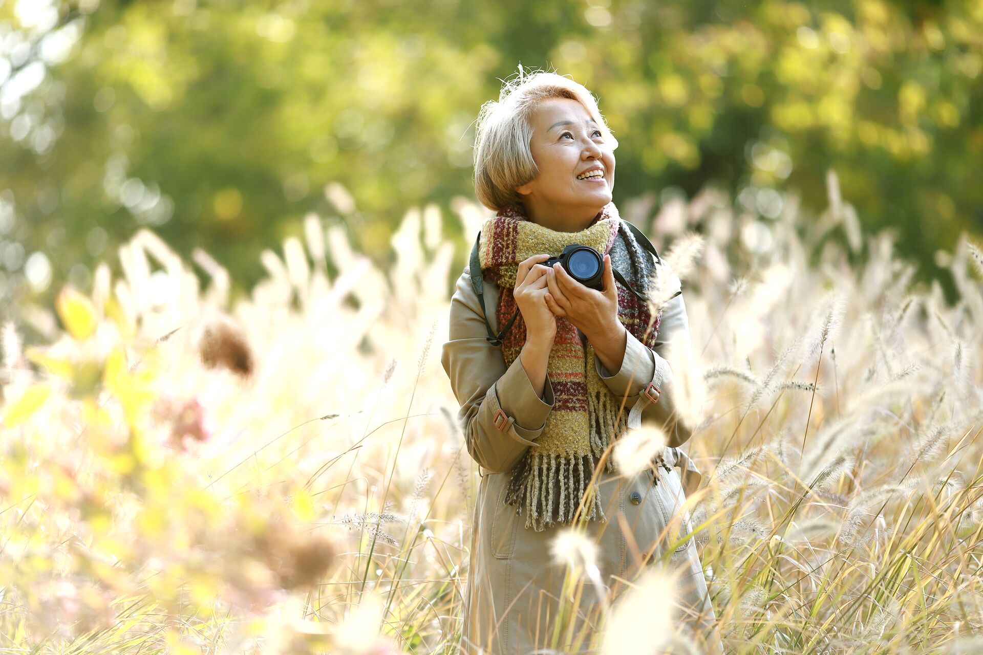 Woman smiling as she takes photos surrounded by greenery