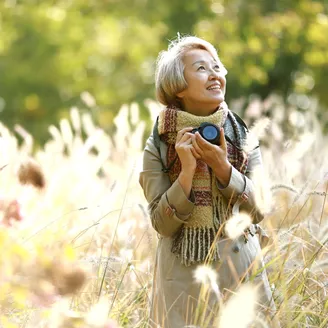 Woman smiling as she takes photos surrounded by greenery