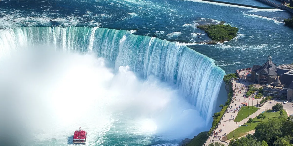 Red boat approaching beautiful waterfall on a beautiful sunny day in Canada