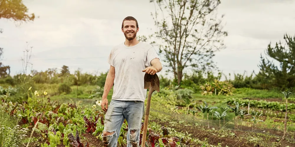 Man stood in field with shovel