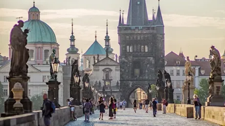 A group of people walking across Charles bridge, Prague