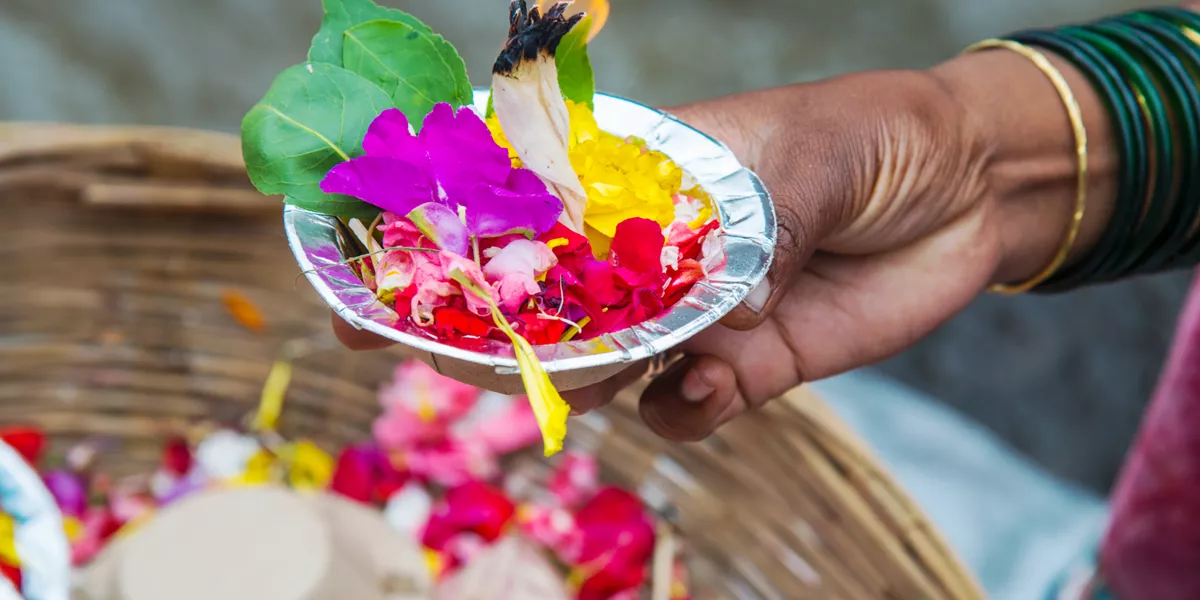 A hand holding a bowl with flowers during Kumbh Mela festival in India