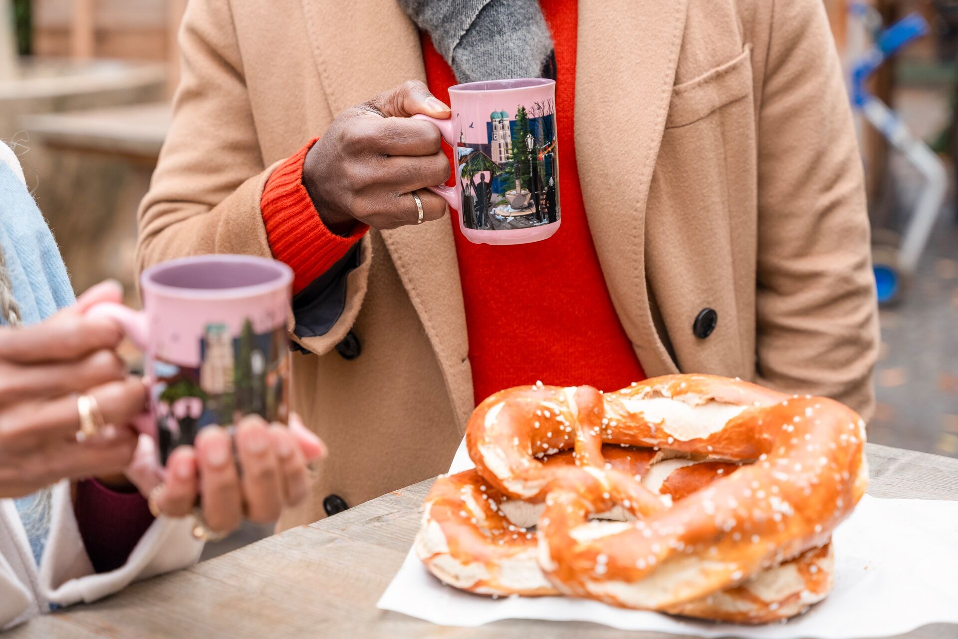Guests at european christmas market in Germany drinking hot chocolate and eating pretzel