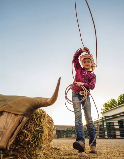 Child playing with a lasso while dressed as a cowboy