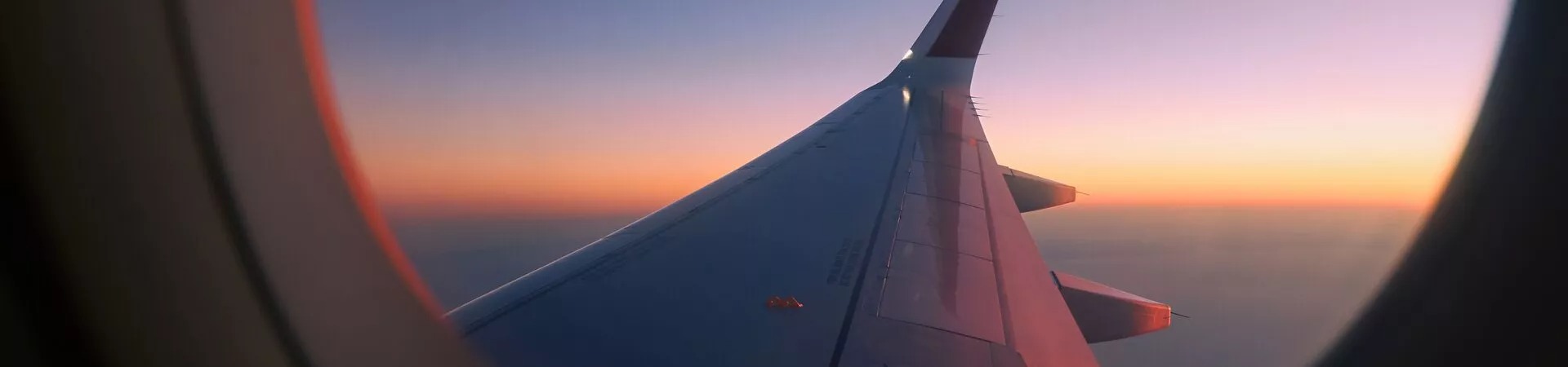 Plane wing at dusk seen through plane window