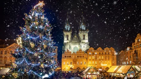 Low angle view of decorated christmas tree and Tyn Church against sky during snowfall at night