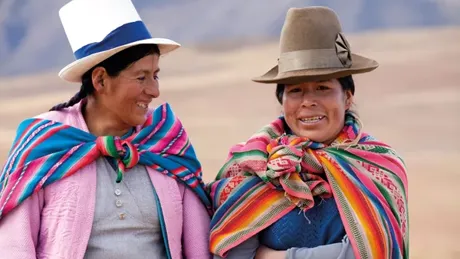 Two Women In Traditional Costume Walking In The Mountains Near Moray Peru