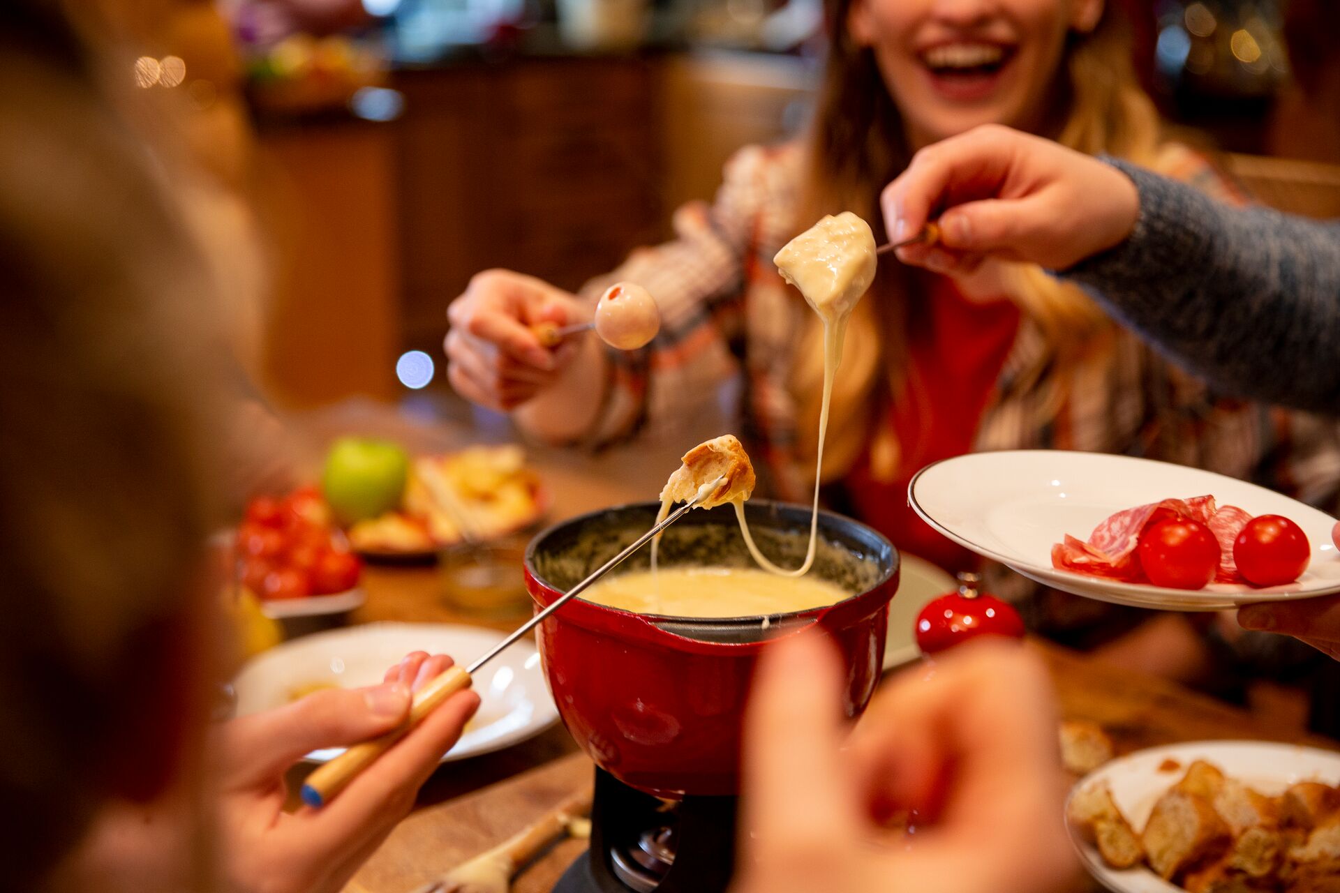 Close-up of Fondue in the foreground, with smiling faces in the backgrund