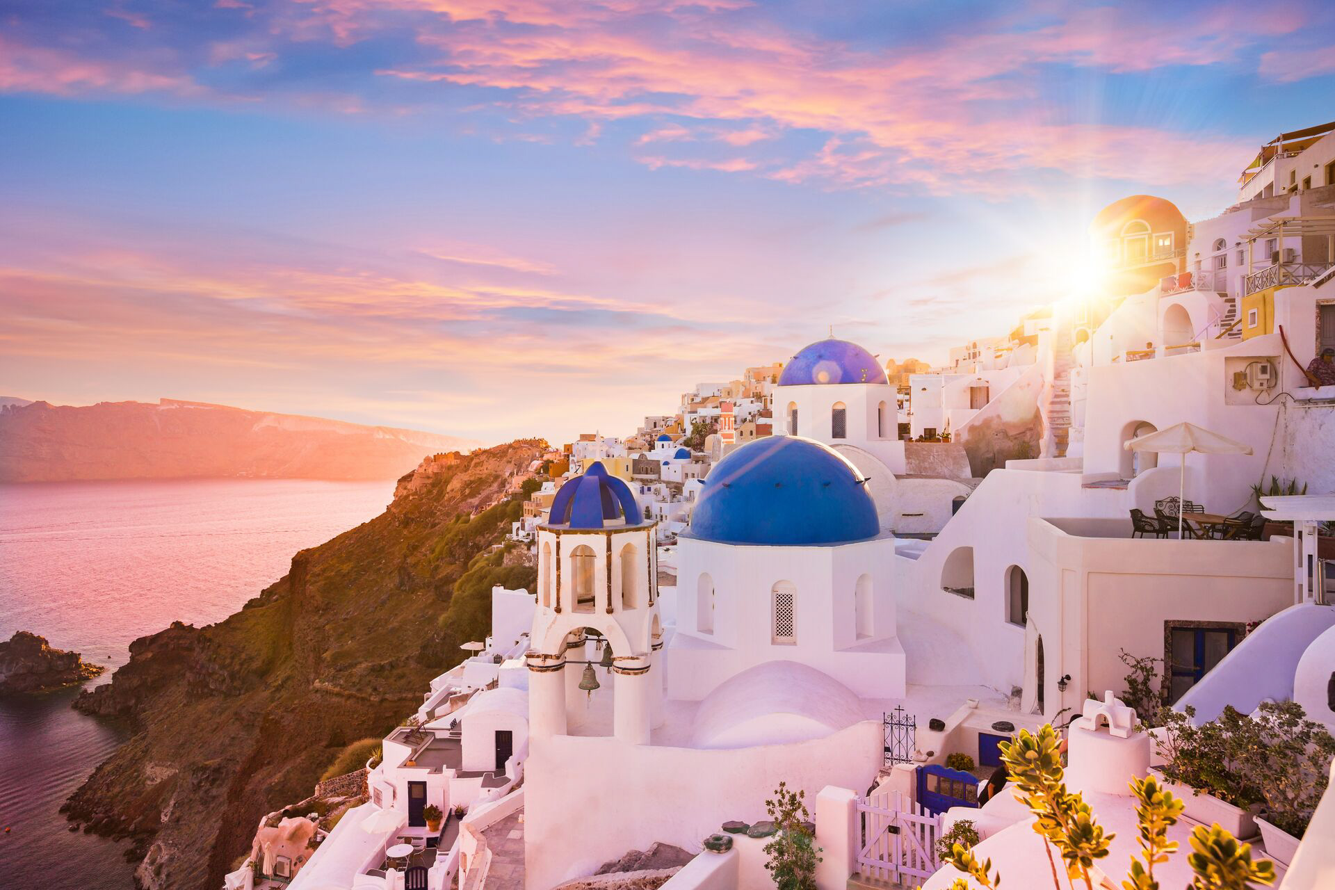 The sun is setting over the blue and white buildings in Greece Santorini 