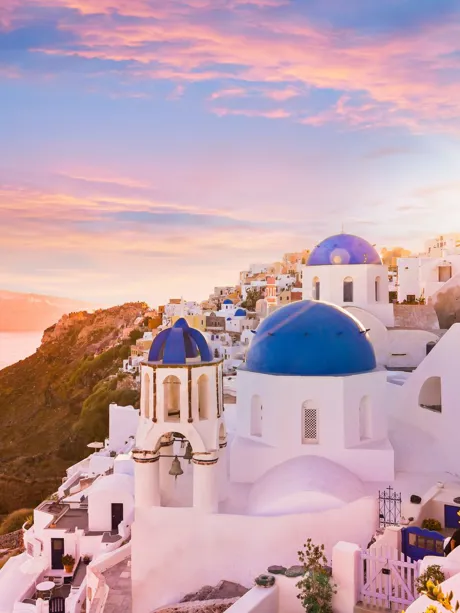 The sun is setting over the blue and white buildings in Greece Santorini