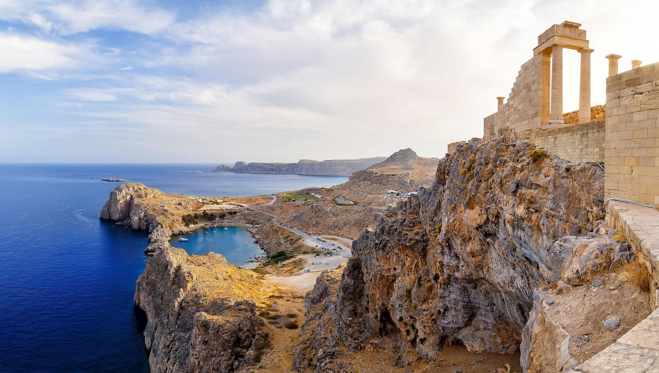 Ancient temple ruins with Doric columns on rocky cliff above blue sea, Lindos, Rhodes, Greece