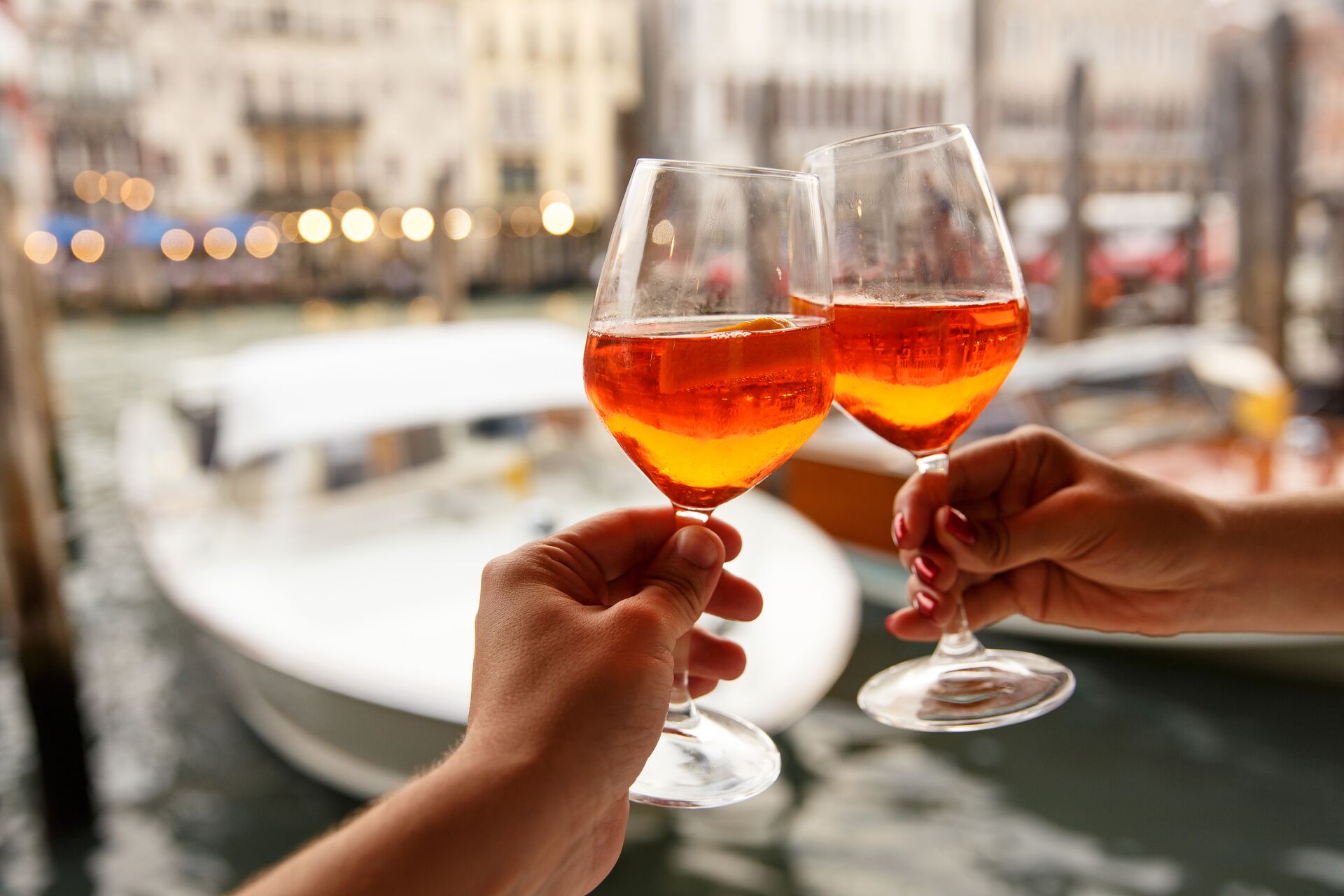 large-couple-clinking-glasses-with-spritz-in-venice-italy-1187599388.jpg