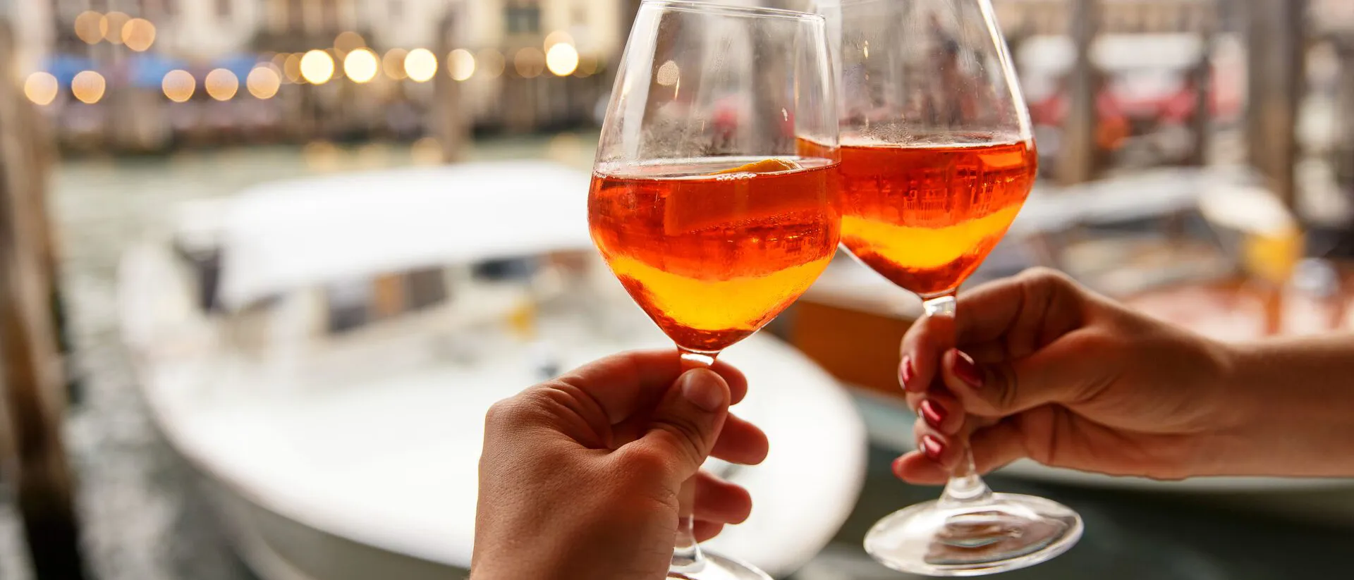large-couple-clinking-glasses-with-spritz-in-venice-italy-1187599388.jpg