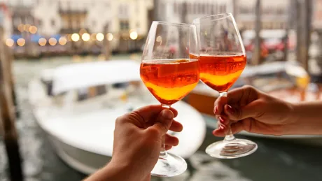 large-couple-clinking-glasses-with-spritz-in-venice-italy-1187599388.jpg