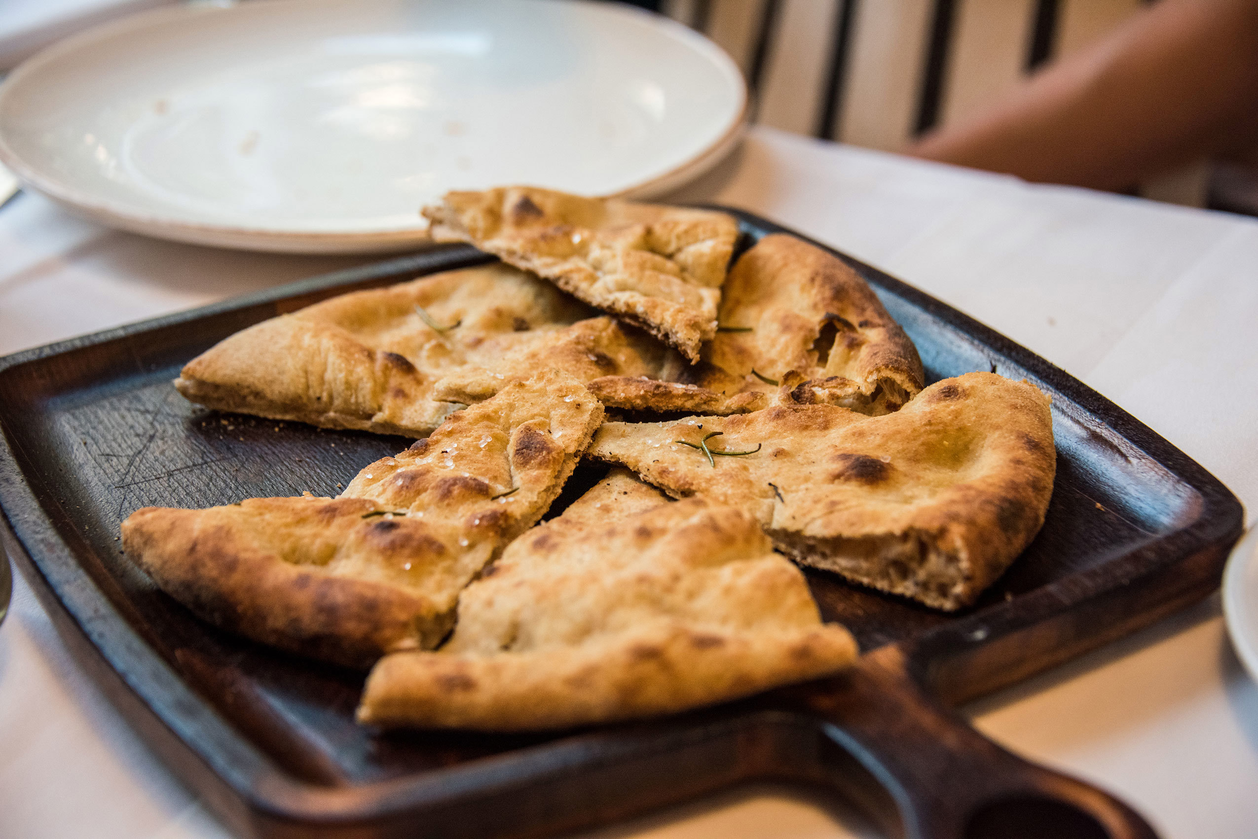 Close up of sliced flatbread on a serving wooden cutting board with handle, in a restaurant in Tirana, Albania
