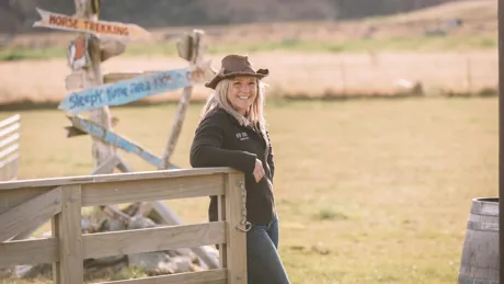 Laura from Real Country Farm in New Zealand standing next to fence