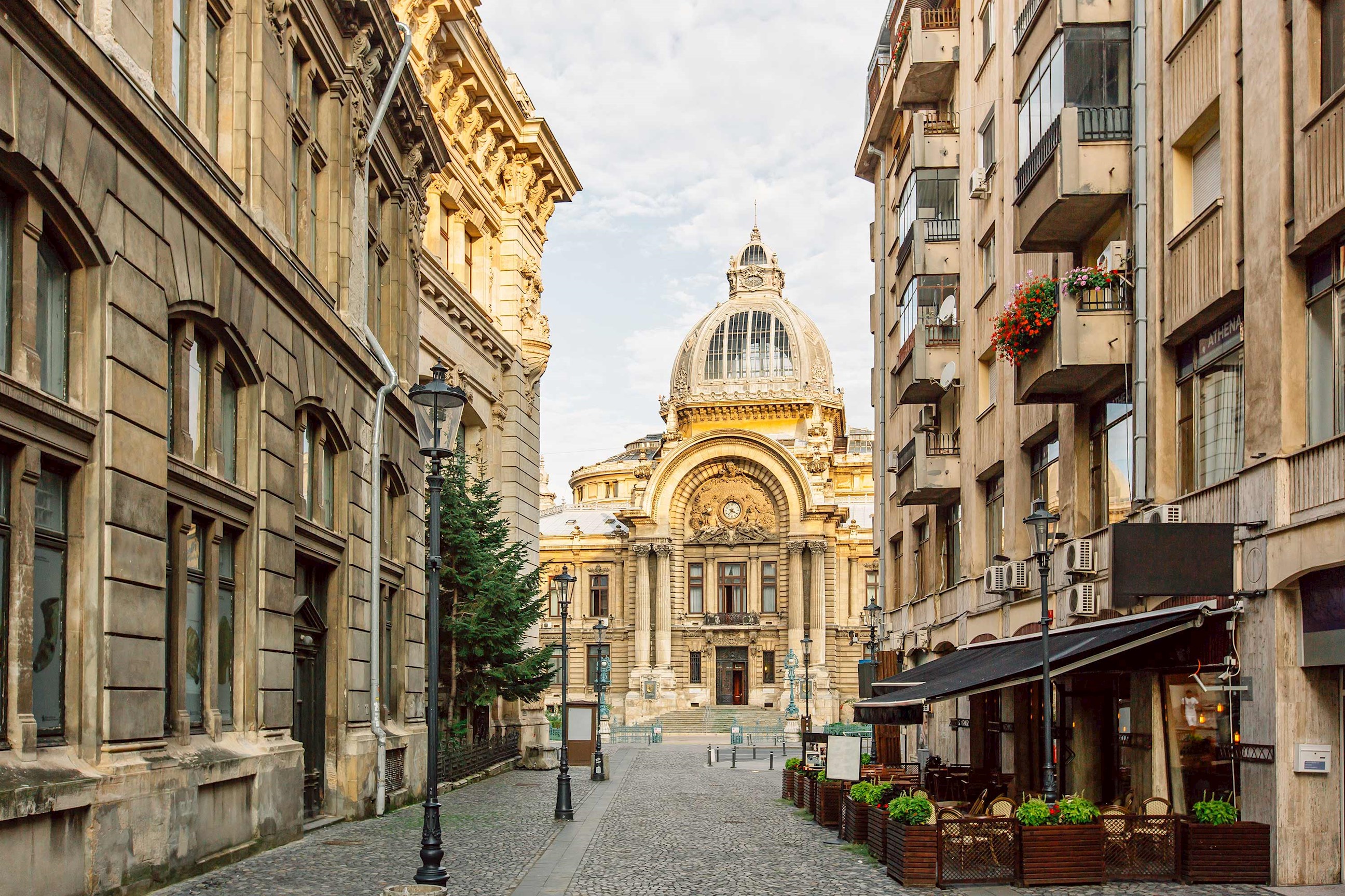 Historic CEC Palace viewed from cobblestone street lined with buildings in Bucharest, Romania