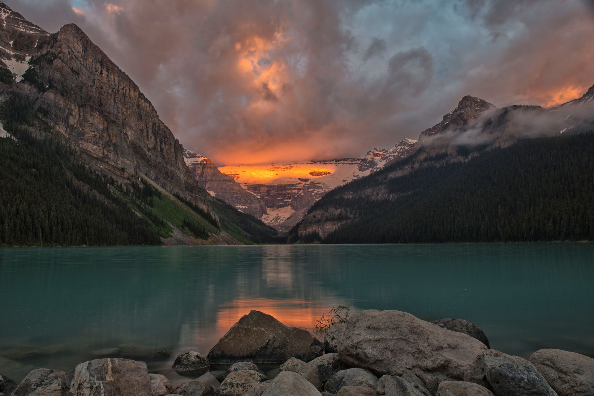 Lake Louise surrounded by steep mountains during sunrise
