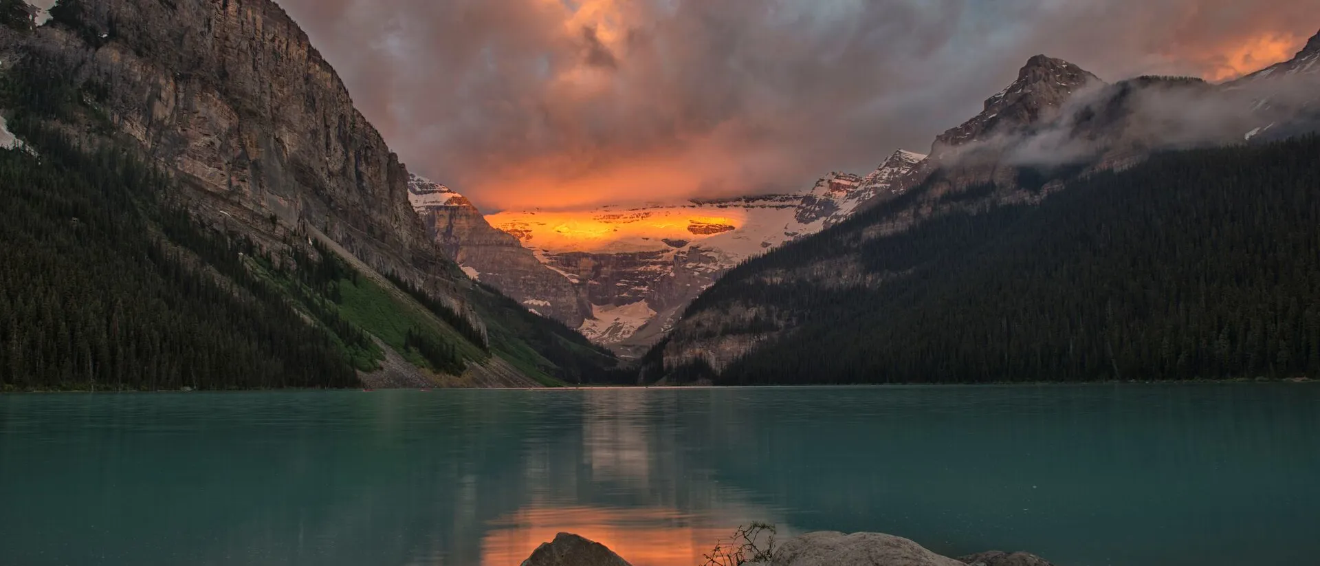 Lake Louise surrounded by steep mountains during sunrise