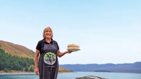 Angie Lake Tekapo holding a plate with cake at the bay, Australia