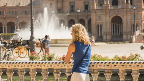 A woman standing on a balcony looking at a fountain