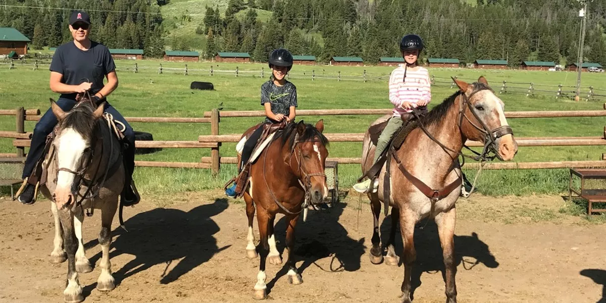 A father with two children enjoying horse riding