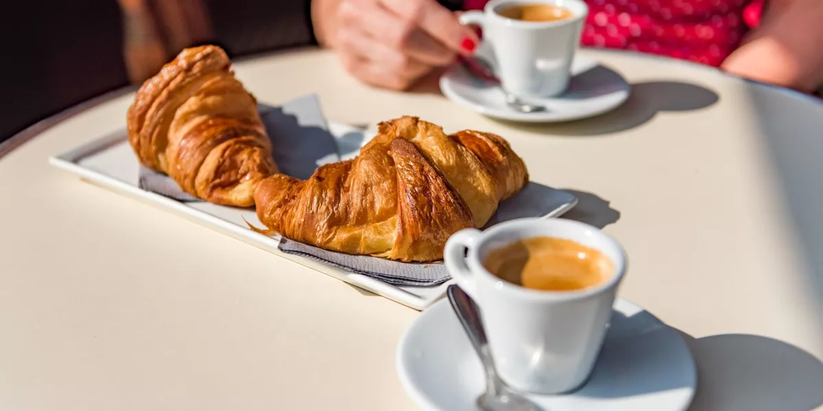 Woman enjoying croissants and coffee in the sun