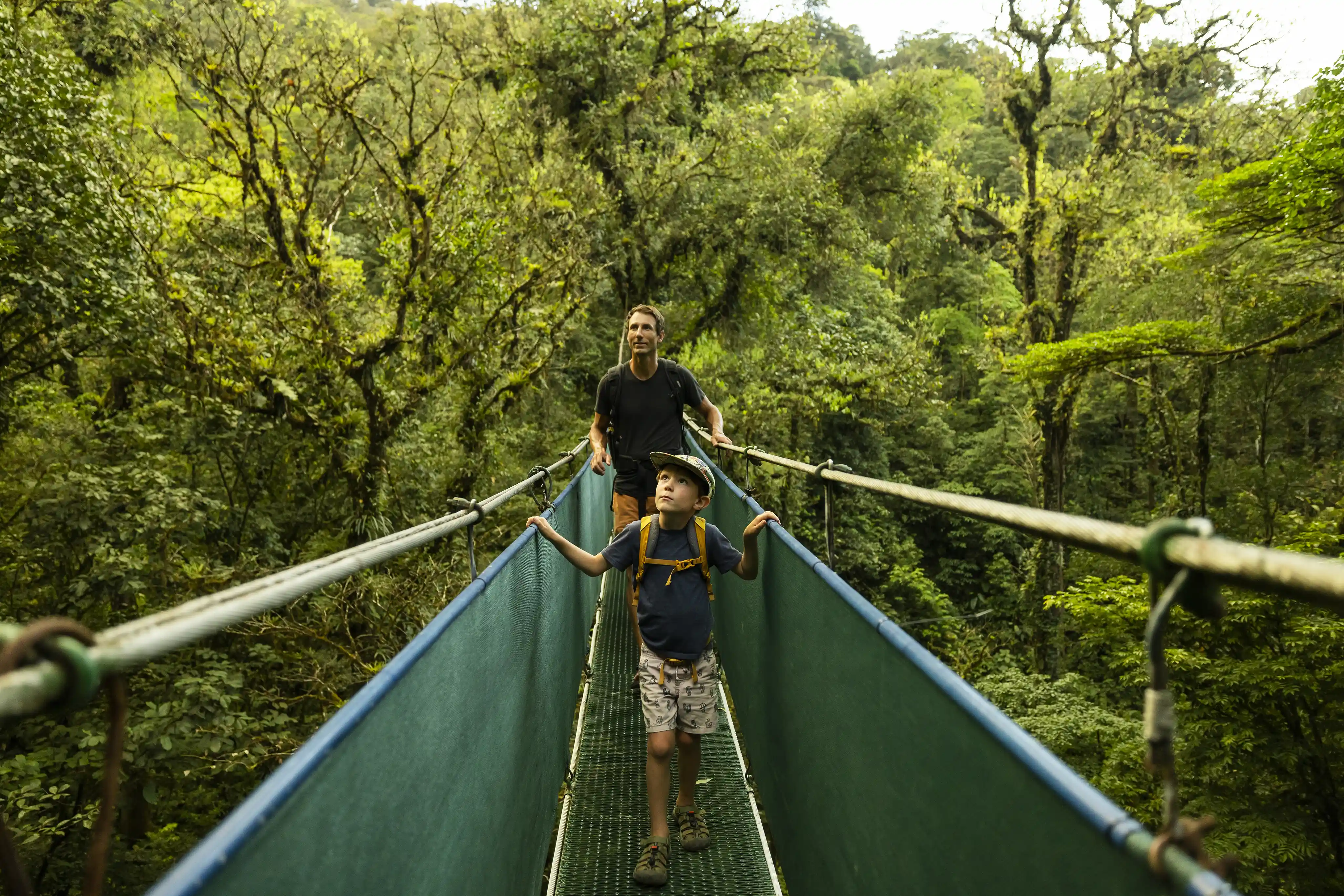 A Father And Son Crossing A Suspension Bridge In Costa Rica