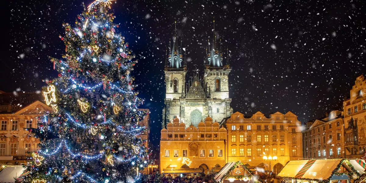 Low Angle View Of Decorated Christmas Tree And Tyn Church Against Sky During Snowfall At Night