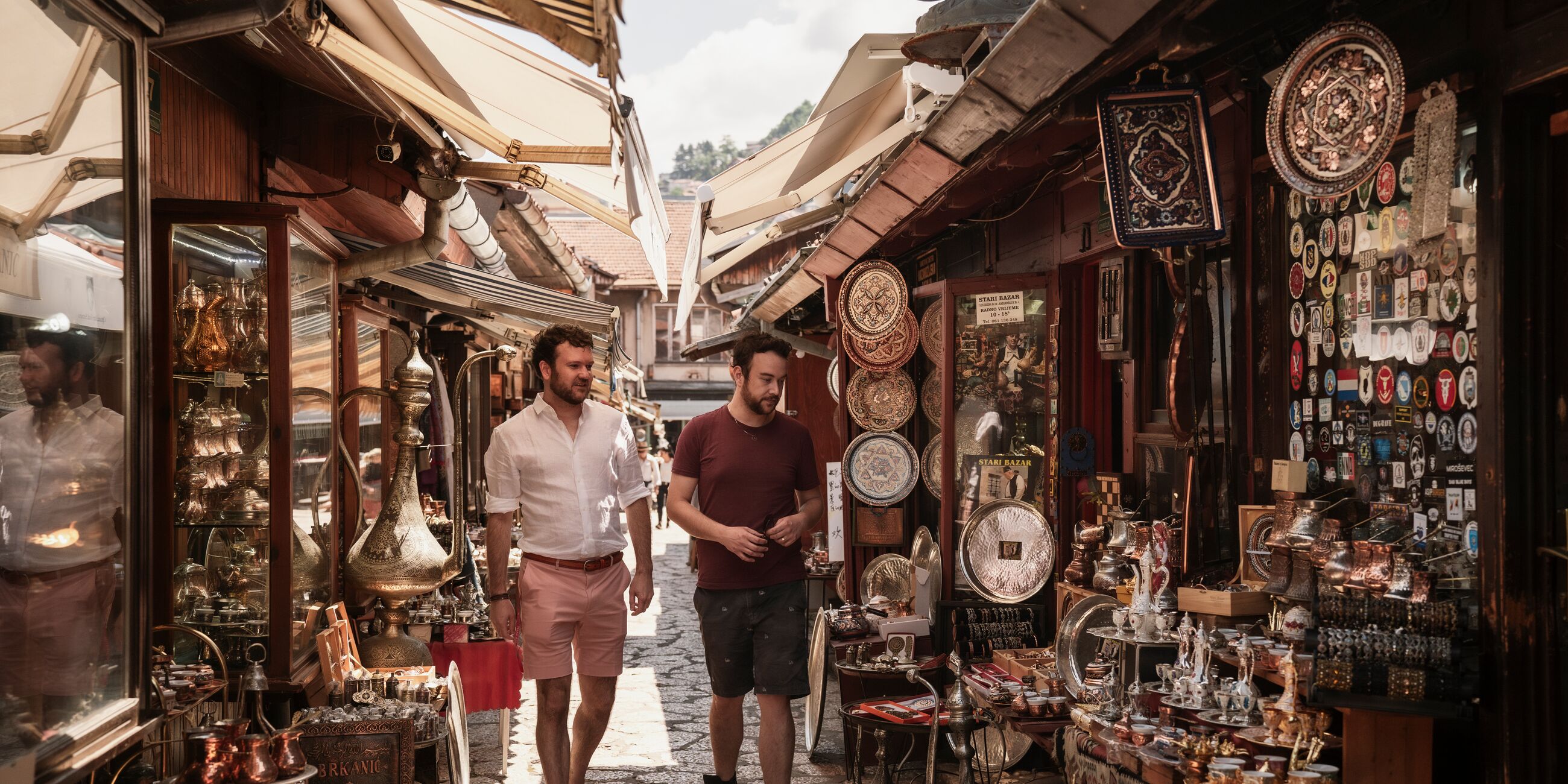 Two men walking down a street next to a store