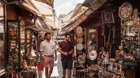 Two men walking down a street next to a store