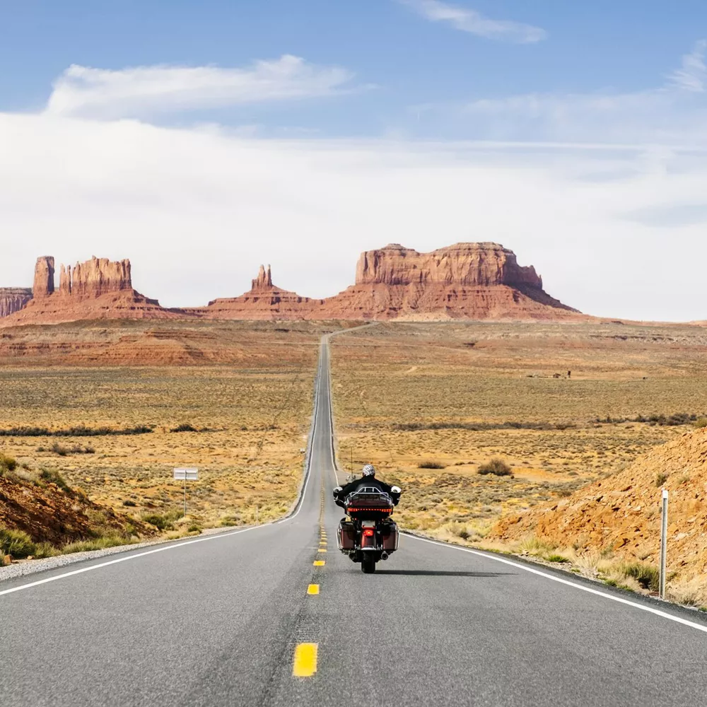 Rear View Of Man Riding Motorcycle On The Desert Road, Monument Valley Tribal Park, Utah