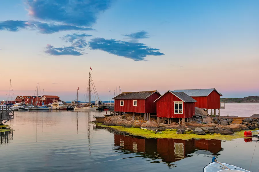 Red and brown wooden house under white clouds during daytime in Sweden