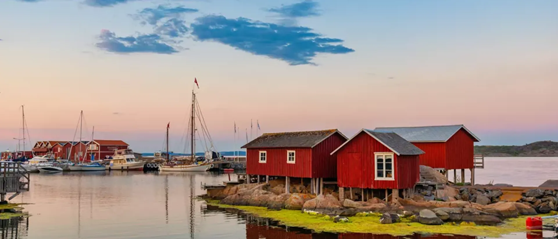 Red and brown wooden house under white clouds during daytime in Sweden