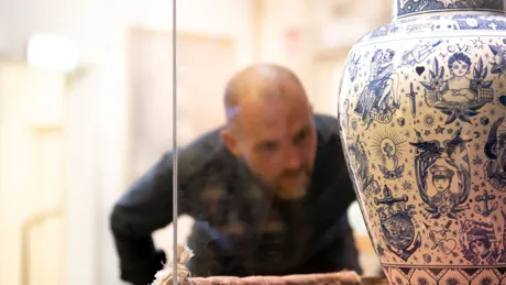 Man looking at white and blue vase