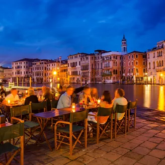 People eating dinner at dusk overlooking the Grand Canal in Venice, Italy