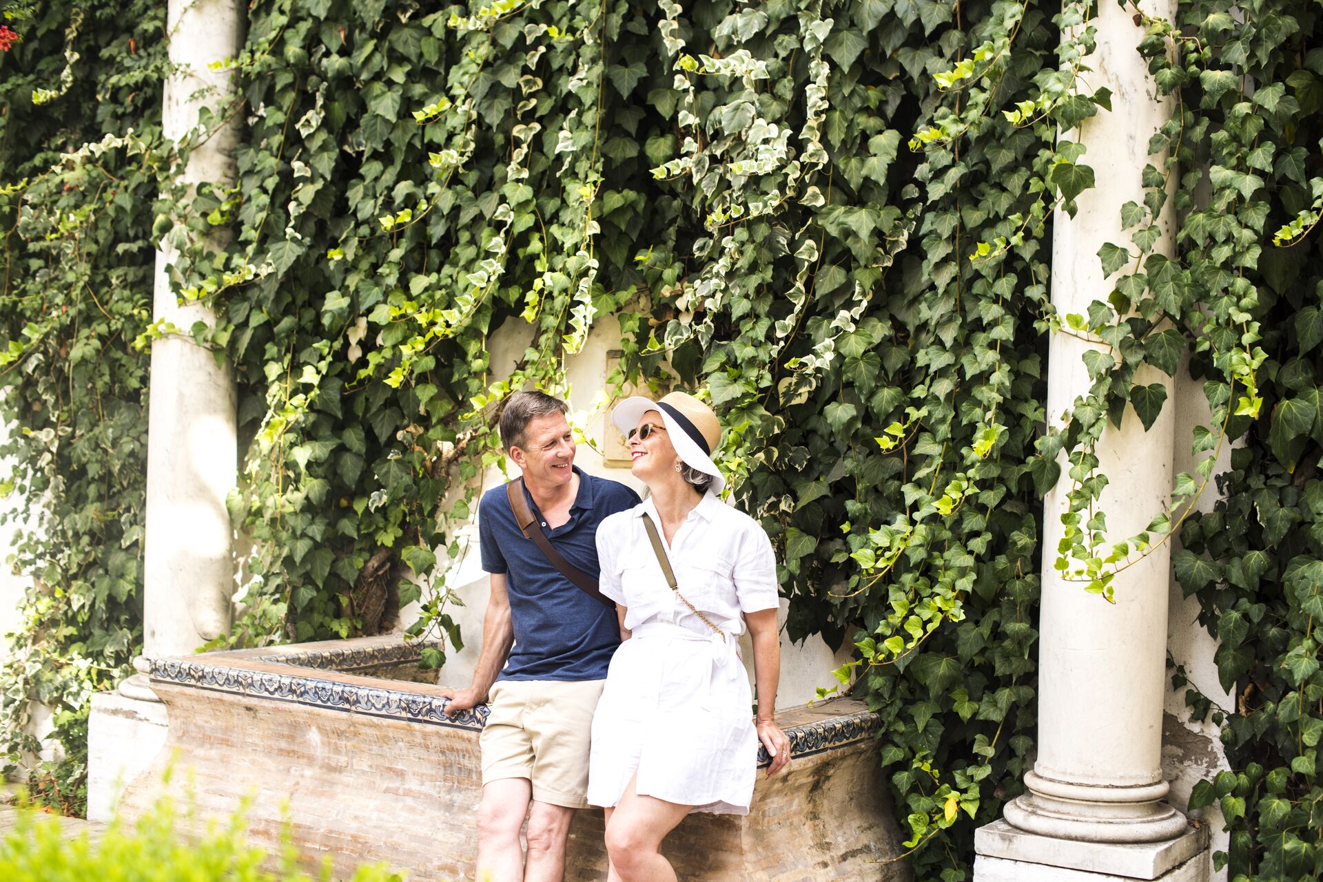 Couple resting on the edge of a fountain while exploring Seville, Spain