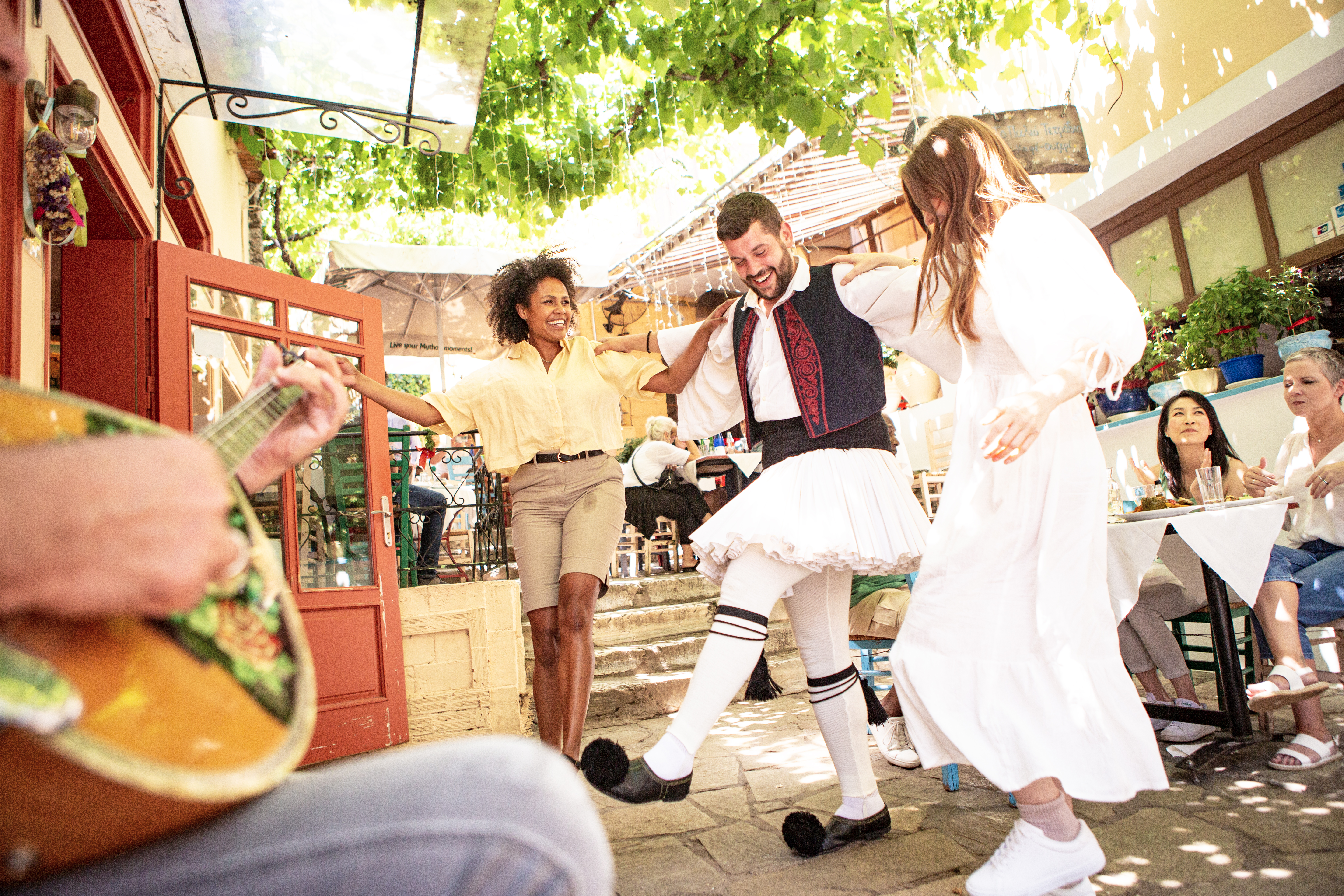 Guests dancing with a local man in traditional Cretan clothes, Greece