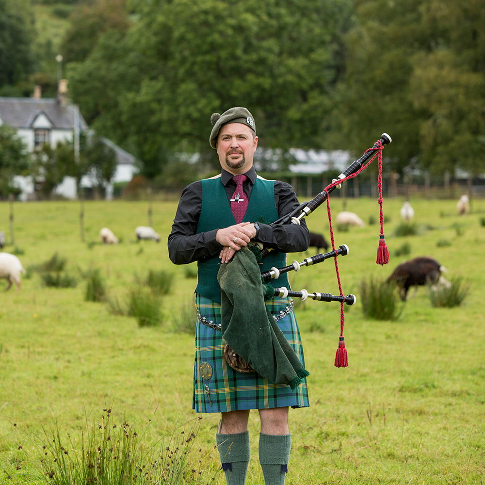 A bagpiper standing in a field in Scotland