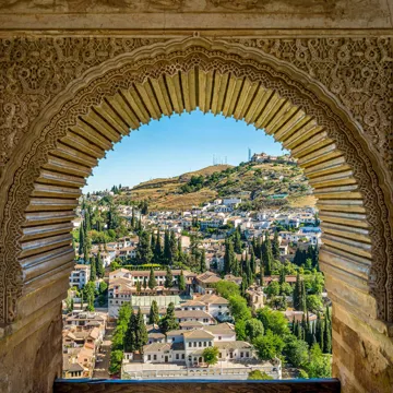 View of Albaicín district through ornate Moorish arch at Alhambra in Granada, Spain