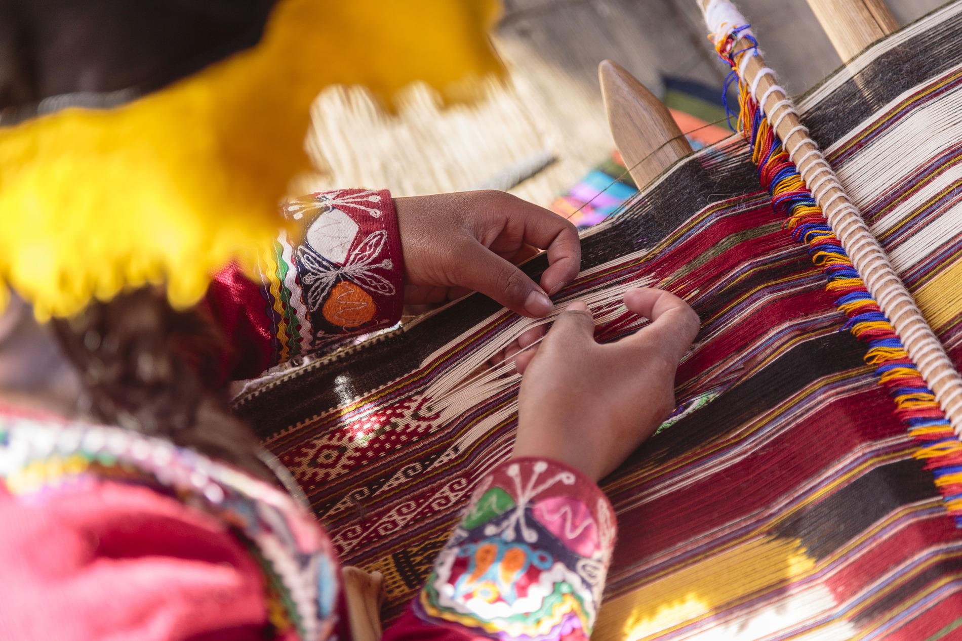 Hands of woman weaving on loom in Peru