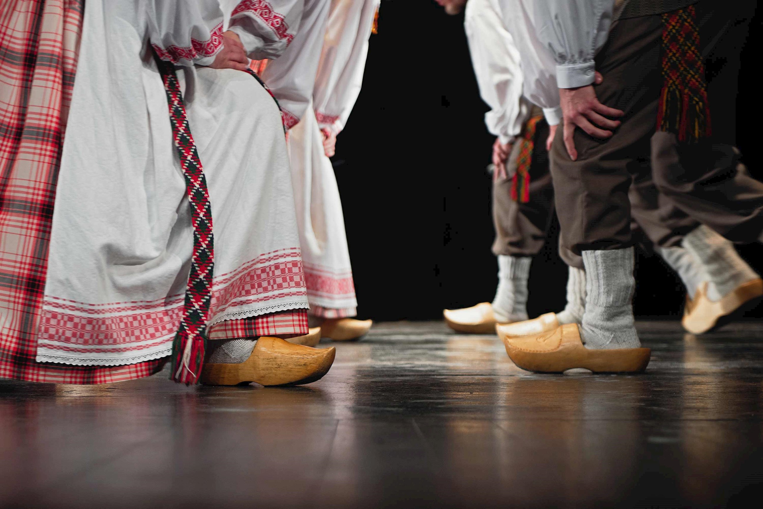 Close-up of traditional Lithuanian folk dancers wearing embroidered costumes and wooden clogs