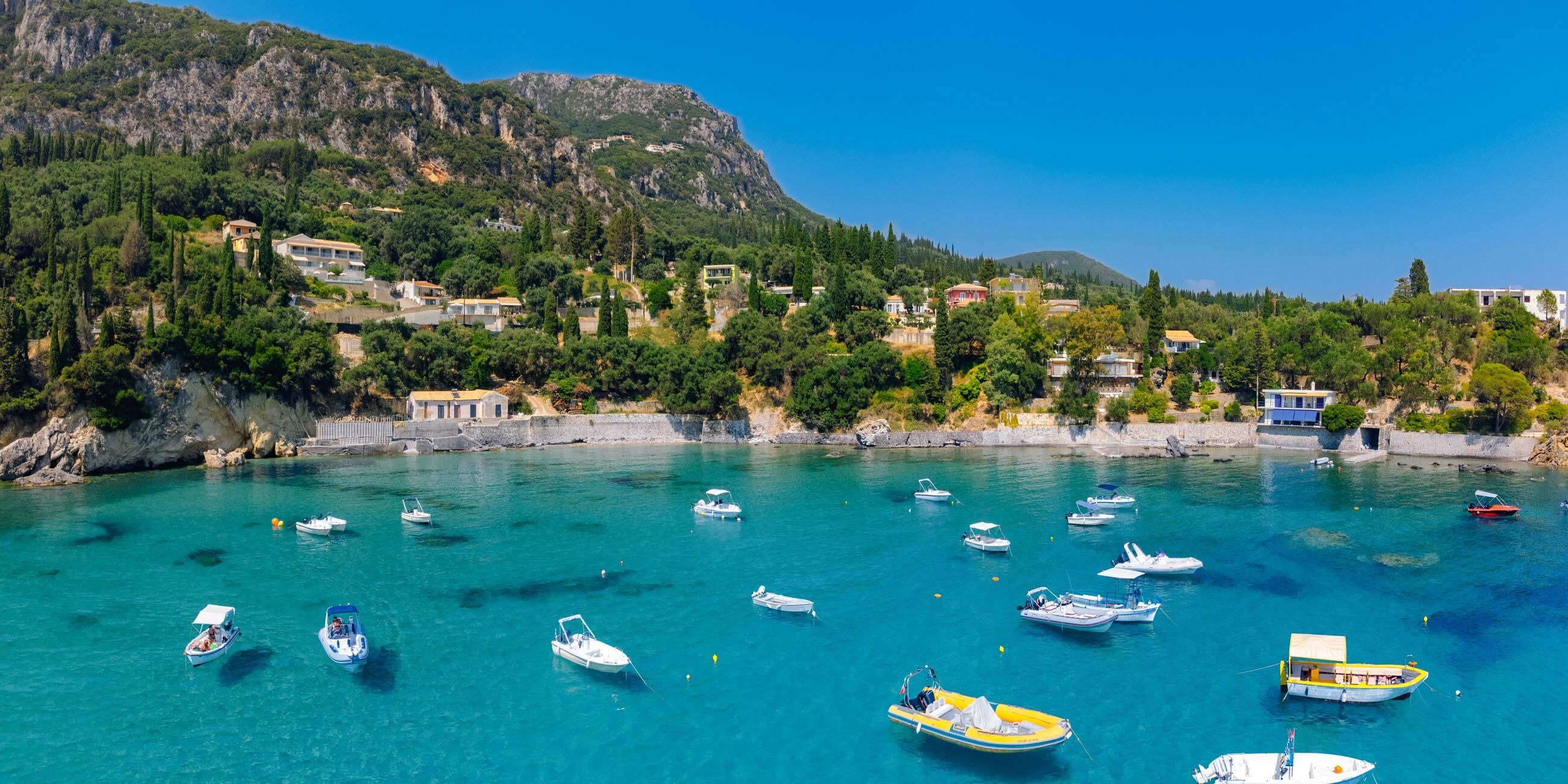 Bay in Greece with houses on mountain slopes and small ships