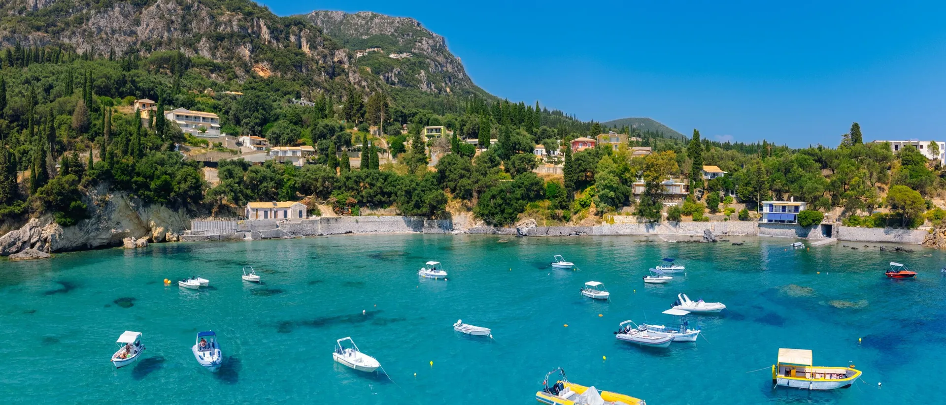 Bay in Greece with houses on mountain slopes and small ships