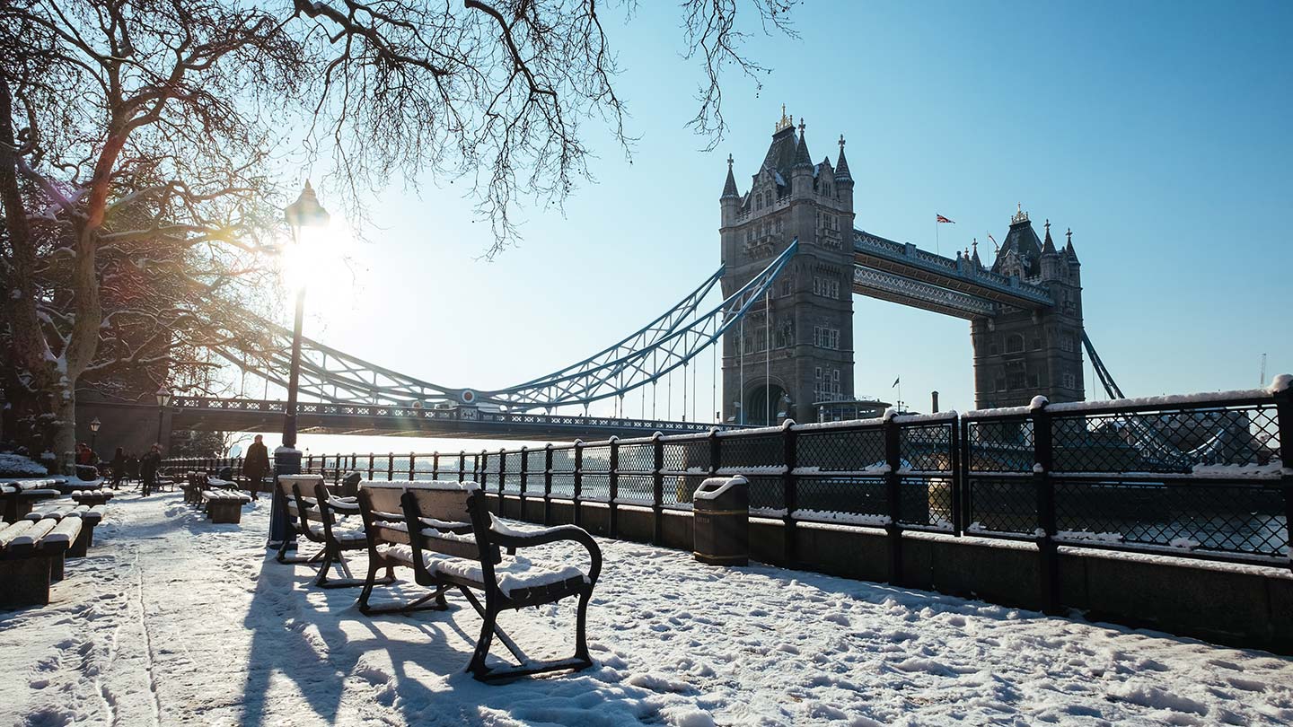 snow covered benches on the South Bank in London with London Bridge in the background in winter